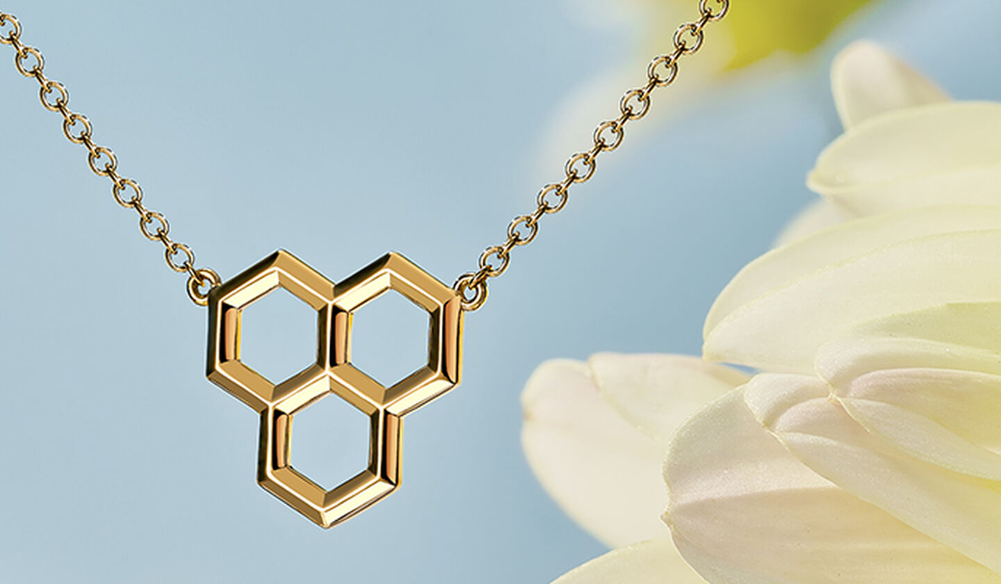 Birks Bee Chic yellow gold pendant necklace on a white daisy flower bakcground.