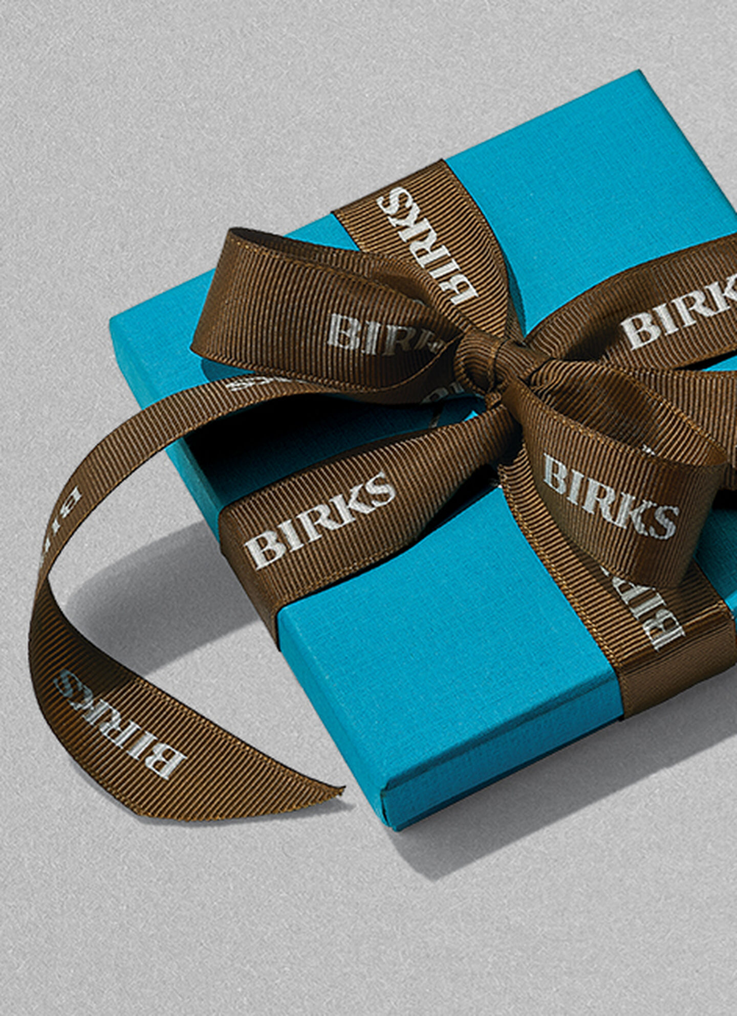 Boîte bleue signée Maison Birks, avec ruban brun.