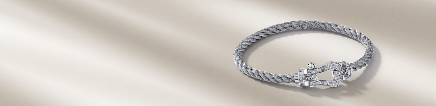 FRED Force 10 white gold bracelet on a beige background.