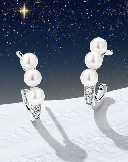 Boucles d'oreilles de Yoko London en perles et diamants sur un fond rose.
