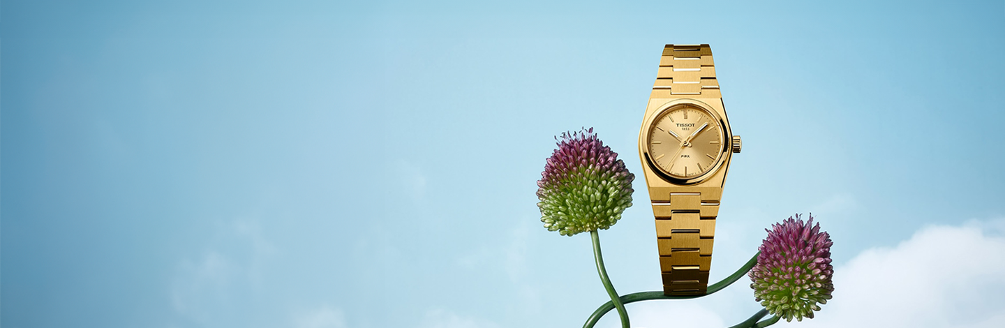 Tissot PRX watch on a blue background.