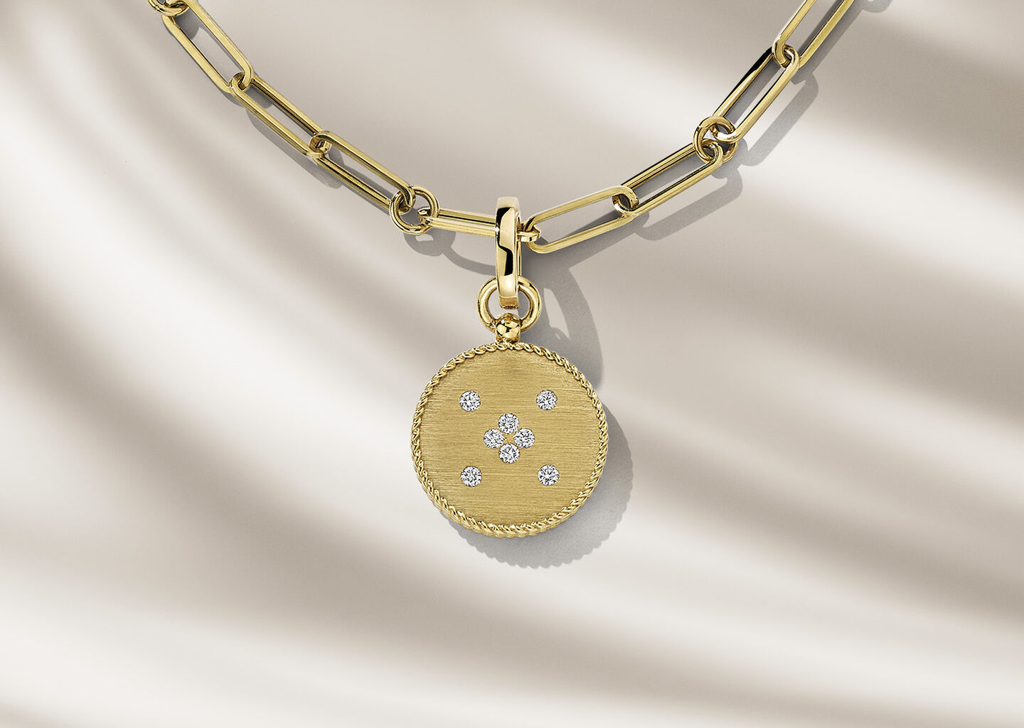 Roberto Coin gold necklace on a beige background.