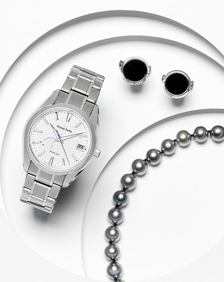 Une montre, les boutons de manchette, et un bracelet sur un fond blanc.