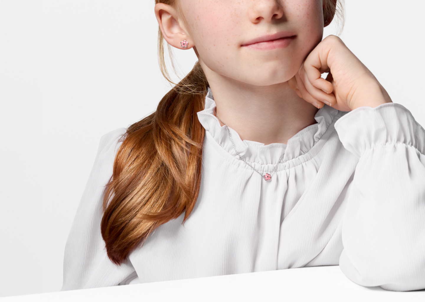 A child wearing a Birks necklace and earrings.