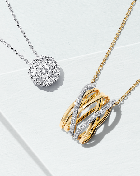 A Birks Snowflake round pavé diamond pendant and a Birks Rosée du Matin pendant with yellow gold and diamonds on a blueish background.