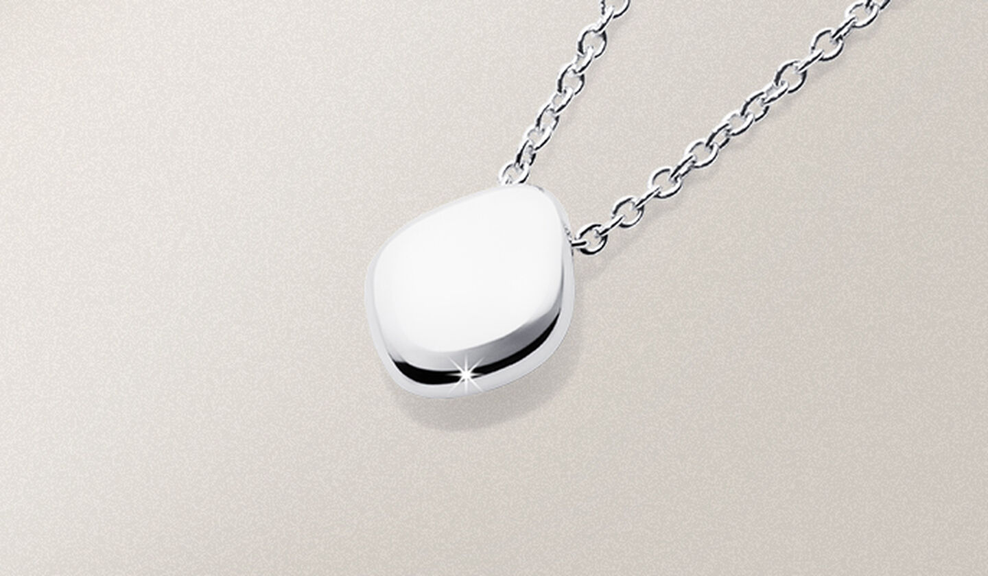 A silver Birks Pebble pendant necklace on a beige background.
