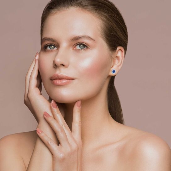 Oval Blue Sapphire and Sunburst Diamond Halo Stud Earrings on model image number 2