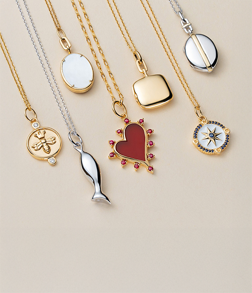 Monica Rich Kosann pendants on a beige background.