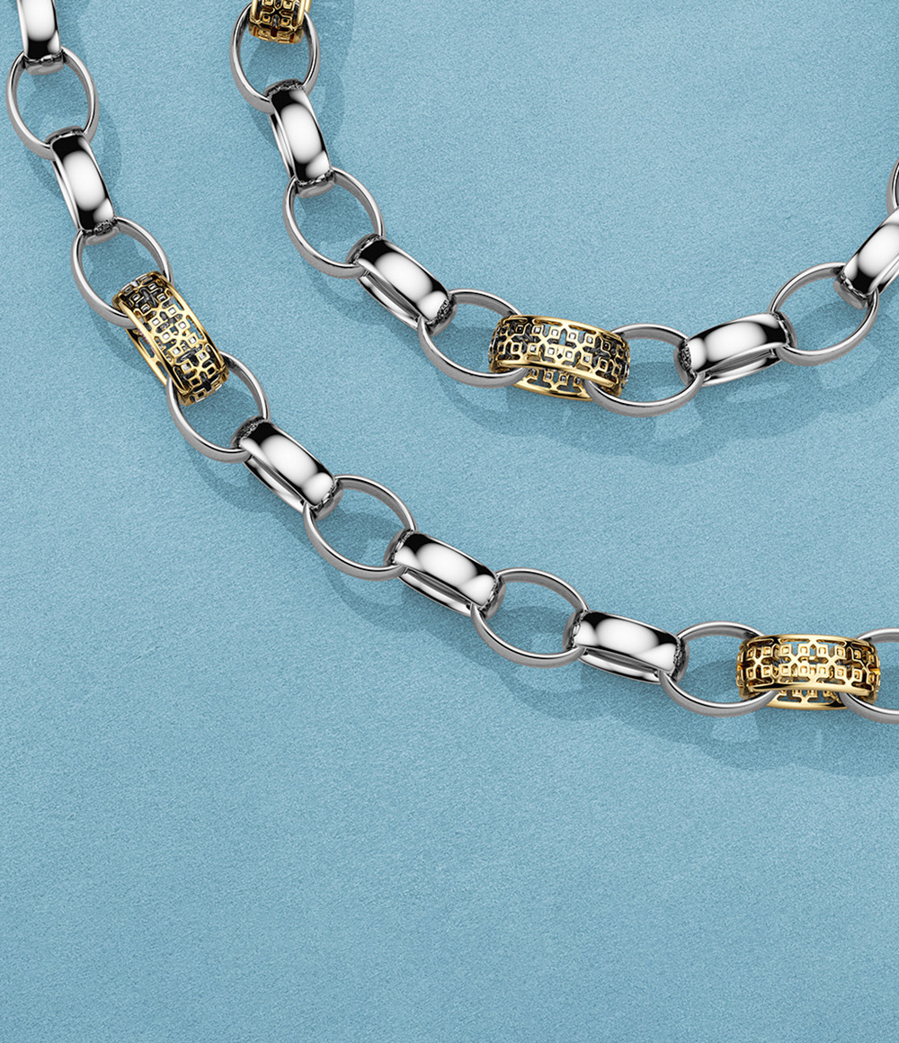 Birks Dare to Dream silver and gold necklace and bracelet on a blue background.